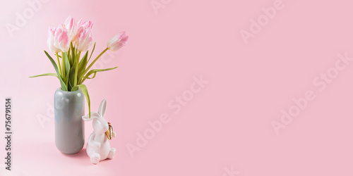Pink tulips in vase and white Easter bunny figurine on pastel pink background #756791514
