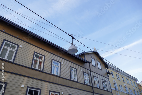 Selective focus of white street lamp, lantern. Beige building on the back. Blue sky with white clouds. Tallinn, Estonia, Europe. February 2024