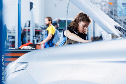 Repair shop technician examines unfunctional car battery using advanced mechanical tools  ensuring peak automotive performance. Employee in garage facility conducts routine vehicle checkup