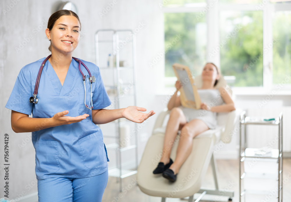 Obraz premium There is medical employee in hospital office. Unrecognizable patient sitting in chair in background. Private outpatient practice. Individual approach to treatment