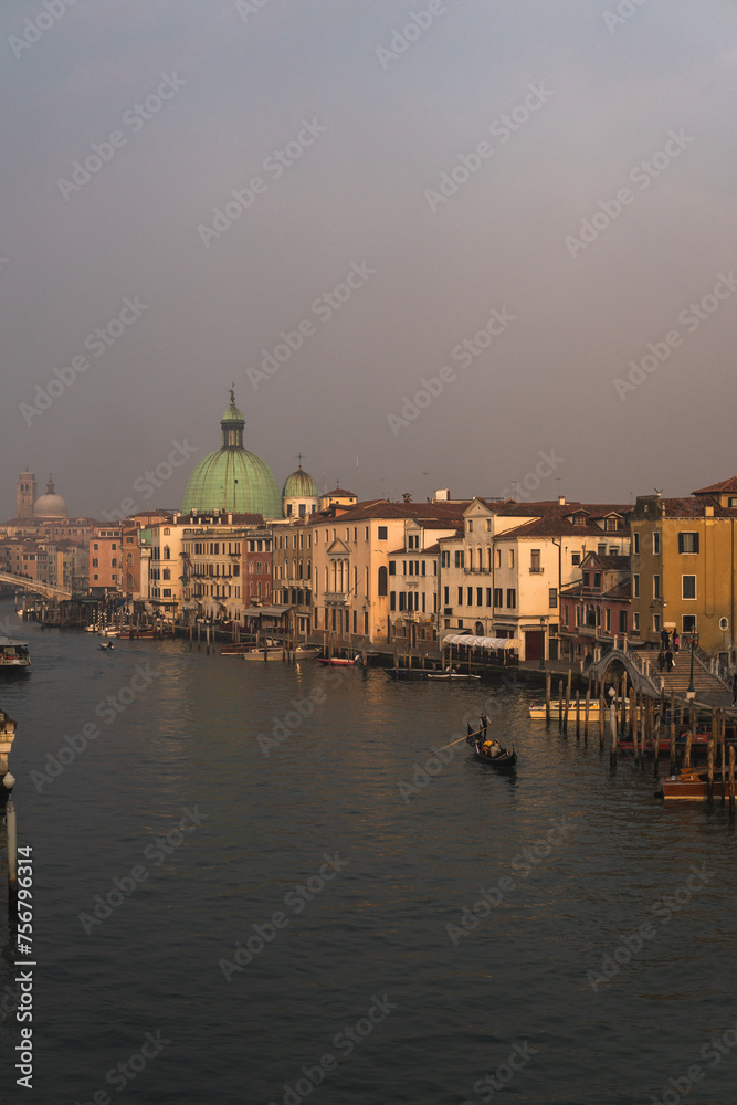Foggy afternoon on Venice's Grand Canal from Fondamenta Santa Lucia, with boats moored, a gondola gliding, and distant views of Chiesa di San Simeon Piccolo’s dome and Chiesa di San Simeone Grande.