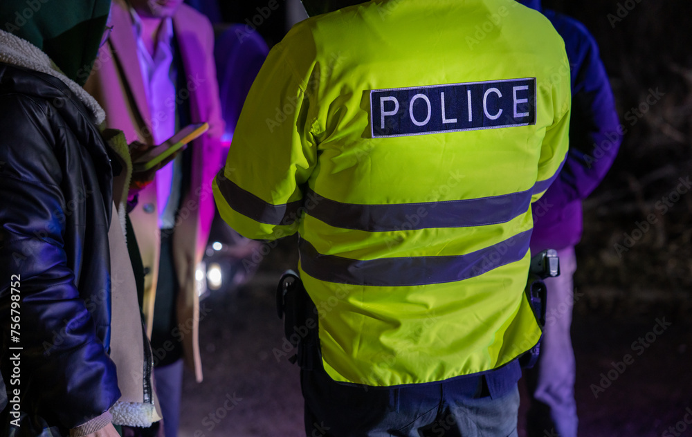 A police officer stands with his back to the car he stopped for speeding. stock photo A police officer stands with his back to the car he stopped for speeding. stock photo