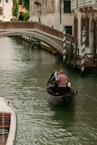 A captivating photo capturing a gondolier skillfully navigating the iconic canals of Venice, Italy, with historic buildings and picturesque bridges forming a charming backdrop against the serene water