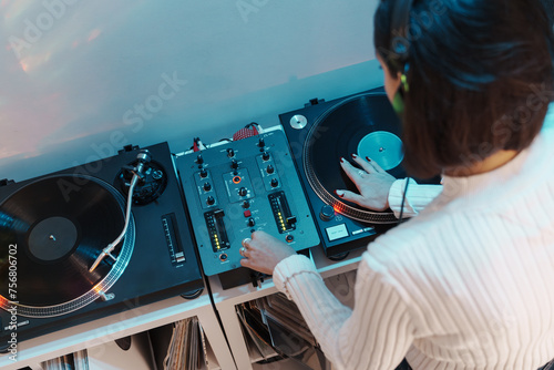A woman DJ in action, using a turntable and mixer to play music. photo