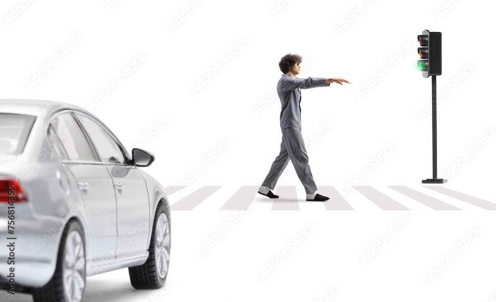Full length profile shot of a guy in pajamas sleepwalking on a street in front of a vehicle