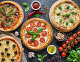 Selection of different pizzas on a black background, top view, close up