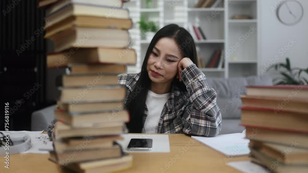 Tired exhausted stressed asian woman student looking from behind large pile of books with sad face while preparing for exams at home Overwork education concept Tired exhausted stressed asian woman student looking from behind large pile of books with sad face while preparing for exams at home Overwork education concept
