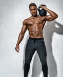 Young muscular man training with kettlebell. Photo of man with naked torso on grey background. Strength and motivation