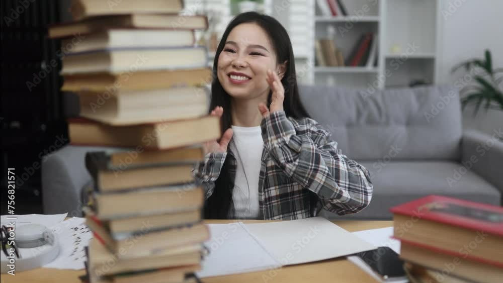Happy smiling asian woman student looking from behind large pile of books with enthusiastic face while studying preparing for exams at home Effective education Happy smiling asian woman student looking from behind large pile of books with enthusiastic face while studying preparing for exams at home Effective education