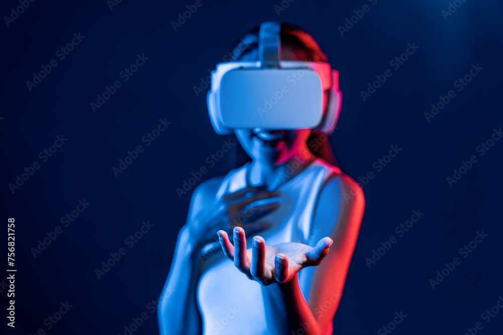 Smart Female standing surrounded by neon light wear VR headset connecting metaverse, futuristic cyberspace community technology. Elegant woman use hand holding generated virtual object. Hallucination.