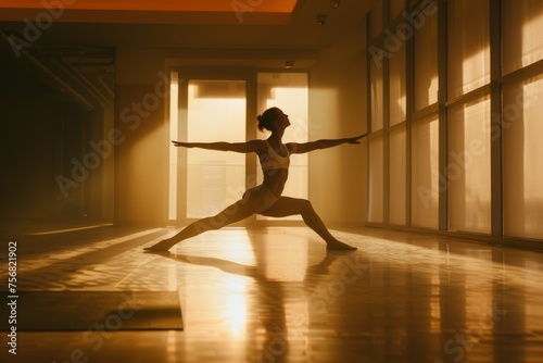 The silhouette of a woman in a yoga pose is highlighted by the warm glow of sunlight in a serene indoor setting