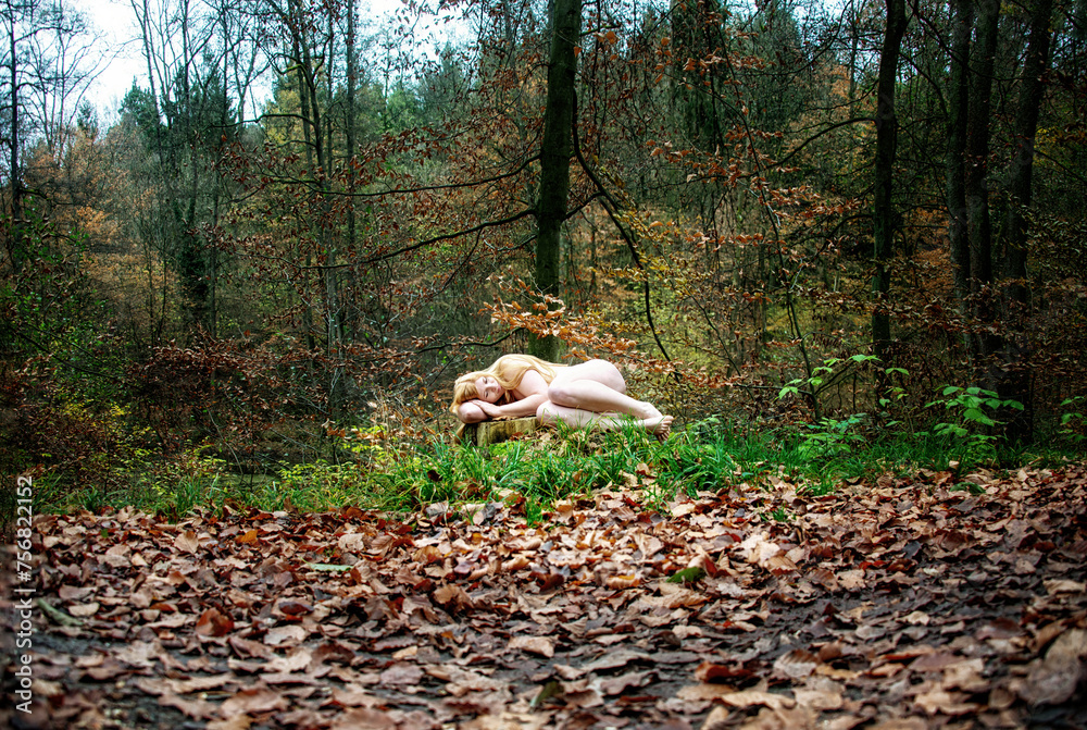 nice young lovely strawberry blonde girl lying naked on a sawed off tree stump in the fall forest - obrazy, fototapety, plakaty 
