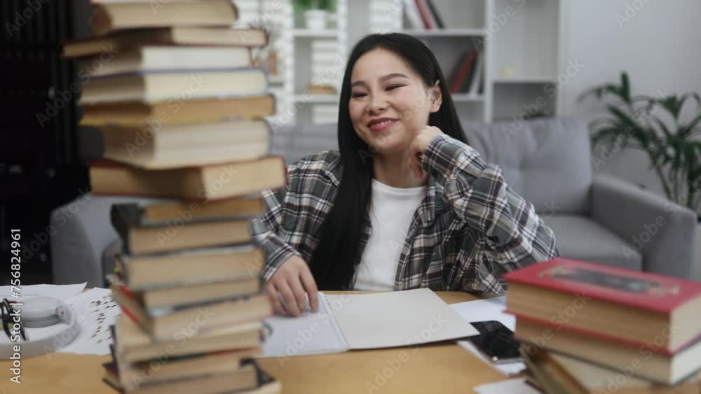 Happy smiling asian woman student looking from behind large pile of books with enthusiastic face while studying preparing for exams at home Effective education Happy smiling asian woman student looking from behind large pile of books with enthusiastic face while studying preparing for exams at home Effective education