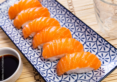 Sake nigiri - tasty dietary sushi with salmon and tuna, soy sauce closeup
