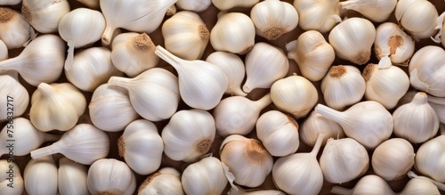 A stack of garlic bulbs arranged in a pattern on a wooden table, showcasing this essential ingredient in cuisine. A closeup shot highlights the natural food growing from the soil