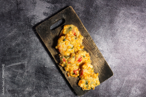 Top view of Bakwan Jagung or Dadar Jagung or Dadar Jagung . Indonesian snack made from corn and flour. Served on a wooden plate.  photo