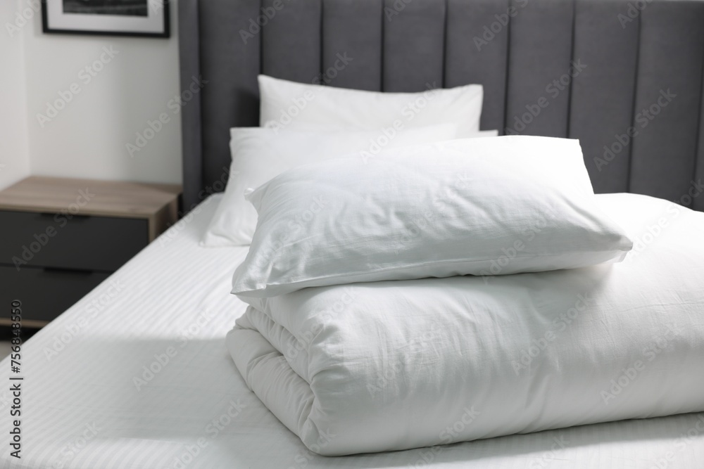 Obraz premium Soft white pillows and duvet on bed at home. Space for text