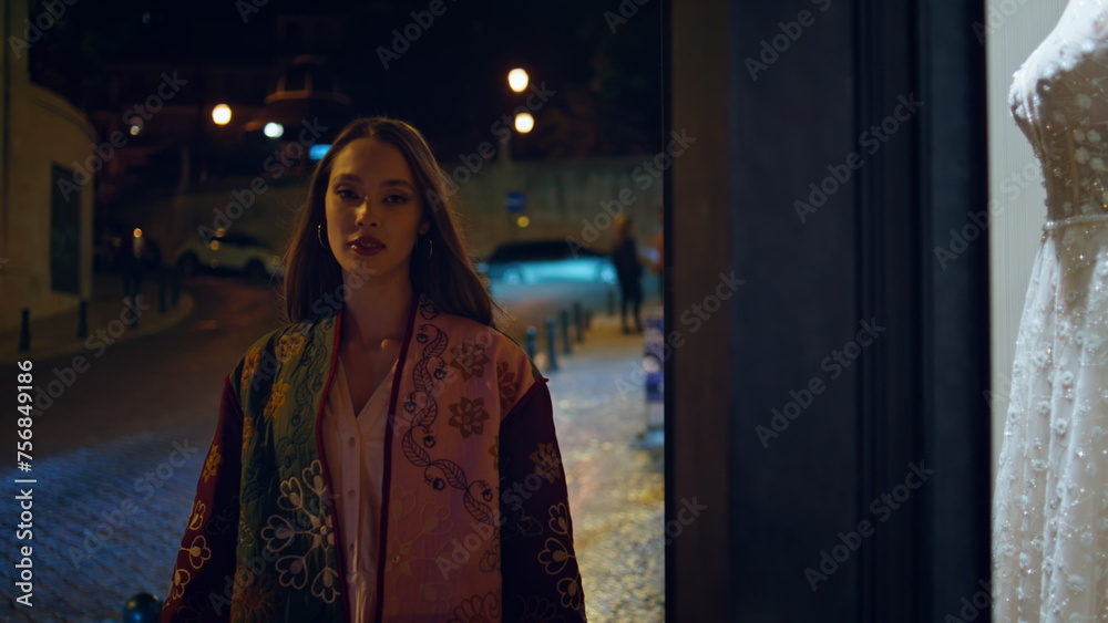 Woman walking wedding shop showcase night city close up. Girl looking dresses