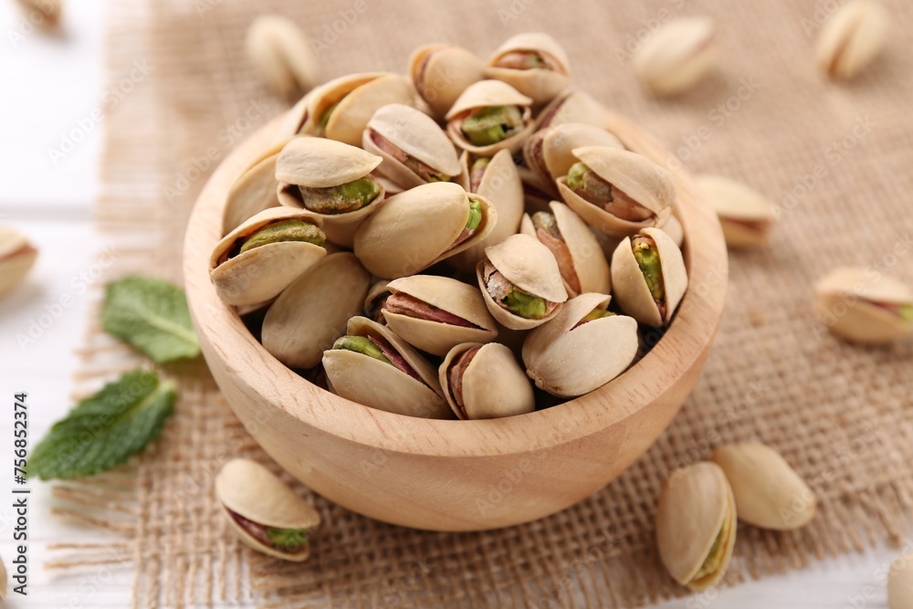 Tasty pistachios in bowl on white wooden table, closeup Tasty pistachios in bowl on white wooden table, closeup