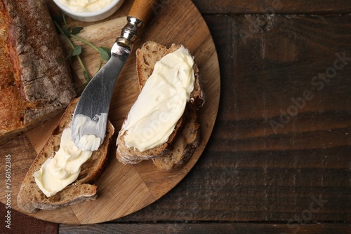 Tasty bread with butter and knife on wooden table, top view. Space for text