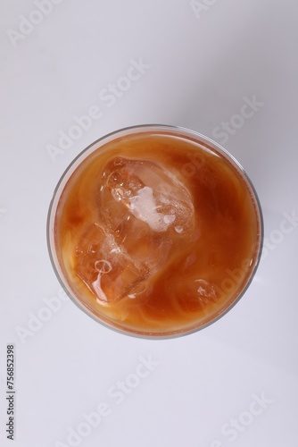 Glass of iced coffee on white table, top view