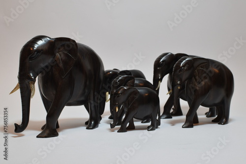 Photography Herd of elephants made of ebony wood in white background