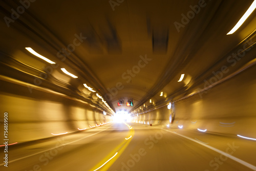 Movimiento rápido. Transitando un túnel curvo en alta velocidad desde un automóvil. Luces ámbar barridas por la rapidez del movimiento. Luz al final del camino. Carretera mexicana. photo