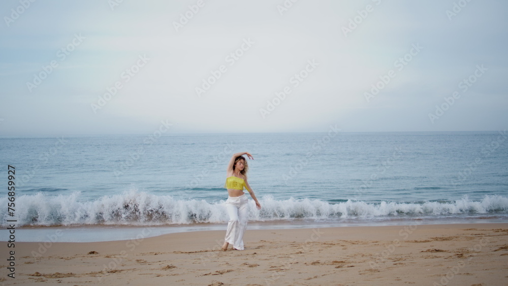 Woman moving body gracefully on sand beach summer evening. Curly girl dancing Woman moving body gracefully on sand beach summer evening. Curly girl dancing