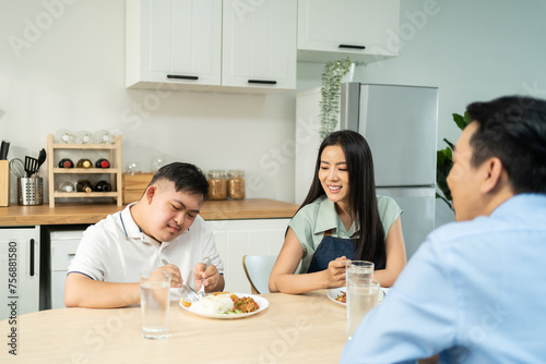 Asian happy family, mature parent having breakfast with son in kitchen. 