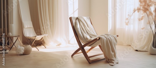 A wooden chair with a cozy blanket draped over it is placed in a room with hardwood flooring next to a window. The room also features a curtain and a warm wood stain on the furniture