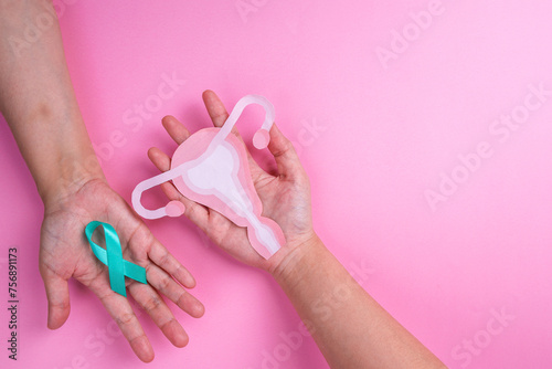 Top View of Female Hands Holding Teal Ribbon and Uterus Cutout. Ovarian cancer and Gynecological Disorders Concept.