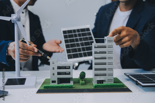 Two Young Engineers Expertise in Solar Cell Installation Meetings and Discussion in The Job. Planning to Install Solar Photovoltaic Panels on Roof Top in The Office Room with Factory Building Plan.