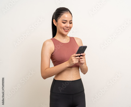 Young beautiful asian woman with sportswear using smartphone on isolated white background. Attractive Portrait latin sporty woman standing pose holding cell phone exercise workout in studio.