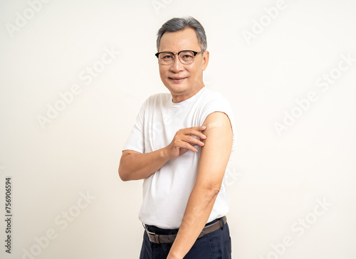 Senior man shows plastered shoulder arm after getting flu influenza vaccine. Mature Old people vaccination immunization. Health care medical.