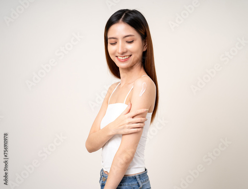 Beautiful smiling happy young asian woman with beauty skin care treatment lotion on the body. Charming female lady standing pose applying body cream Facial treatment beauty and spa
