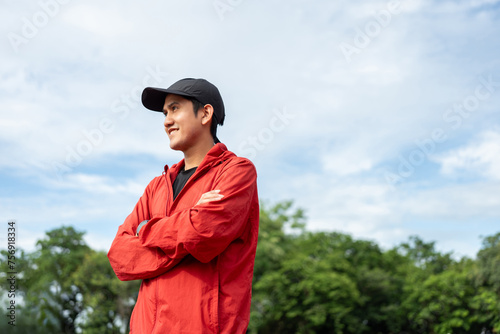 Young handsome asian man wearing sportswear standing post on running track at sport stadium outdoor. Portraits of Indian man jogging on the road. Training athlete outdoor concept.