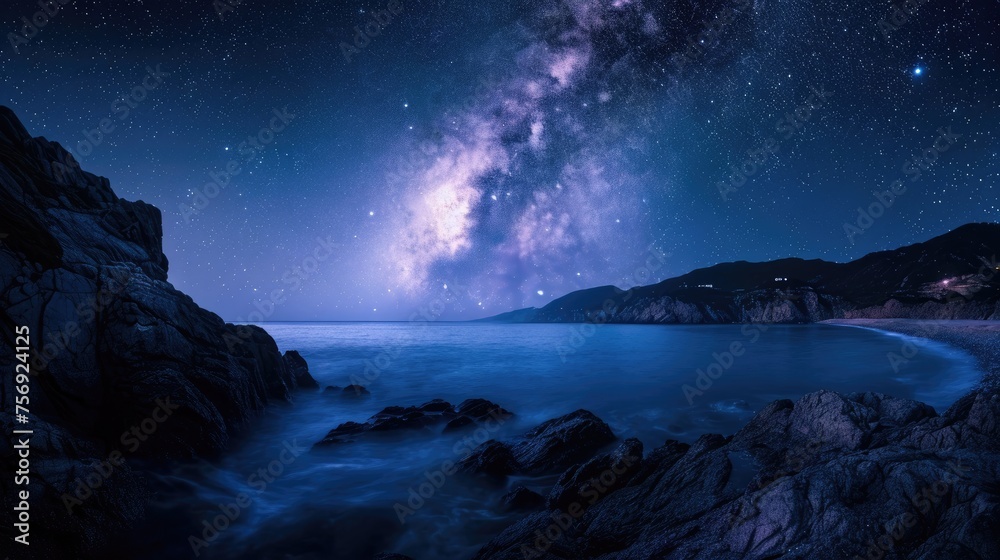 Milky Way galaxy over the ocean with rocky coastline in the foreground