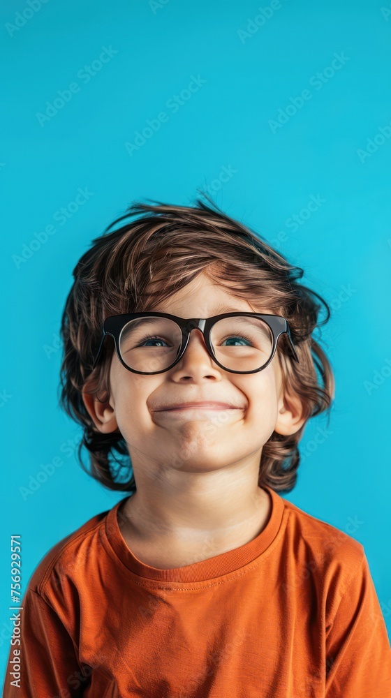 Portrait of a little boy with glasses on a blue background.