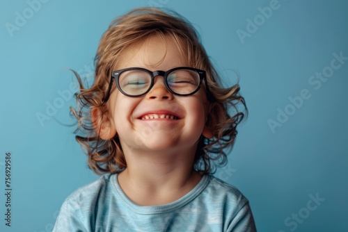 Portrait of a little boy in glasses on a blue background.