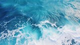 Aerial view capturing the turquoise hues of ocean water, with splashes and foam creating a captivating natural abstract texture.