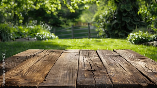 An old  empty wooden tabletop with a fresh green garden in the background.