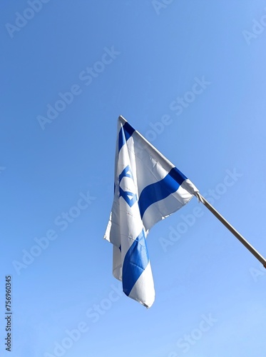 Resilience Amidst Sorrow: Israeli Flag Hanging against Clear Blue Sky