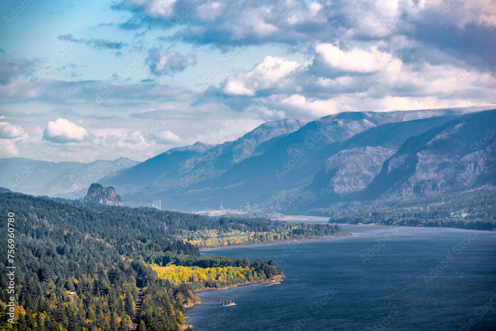 View of the Columbia River Gorge with winding coastlines with forested mountain ranges and low cloudy skies