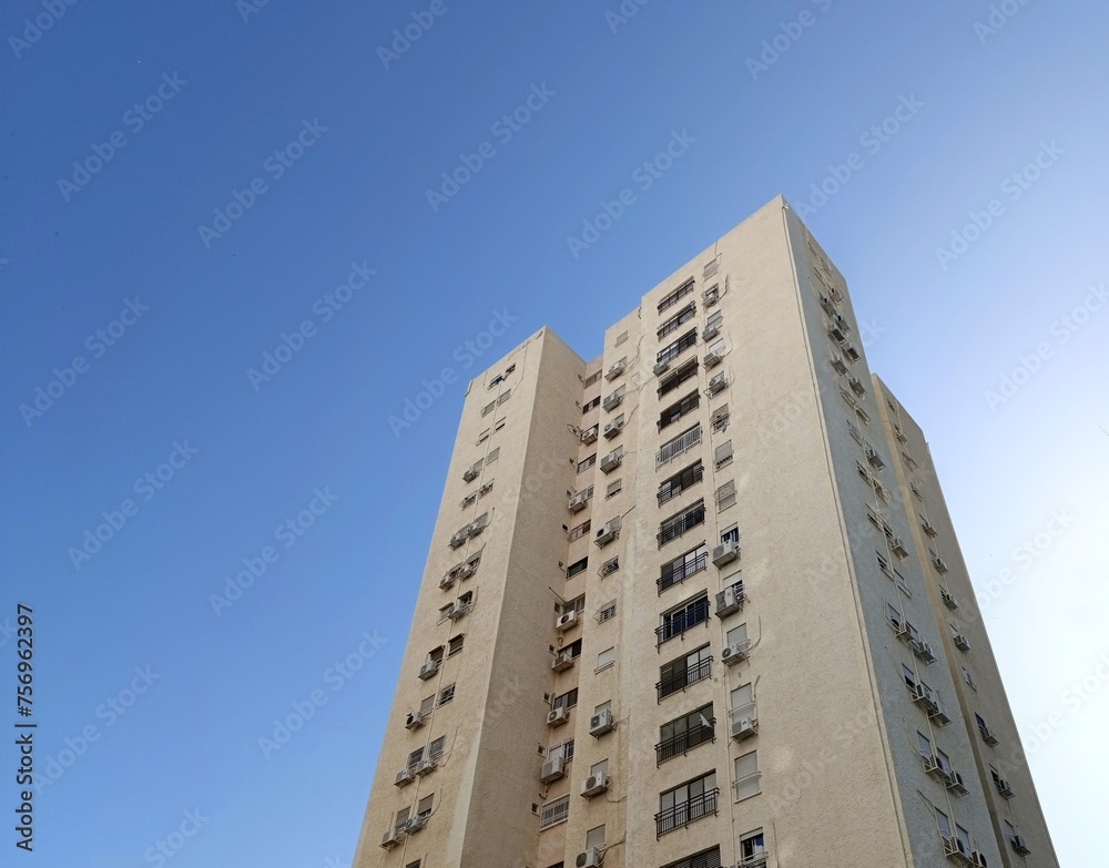 Low angle view of a residential tower block against soft blue sky Low angle view of a residential tower block against soft blue sky