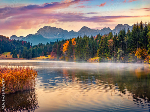 Calm morning scene of Wagenbruchsee lake with Kaltwasserkar Spitze mountain range on background. Misty autumn sunrise in Bavarian Alps, Germany, Europe. Beauty of nature concept background..