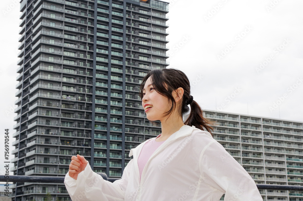 高層住宅が並ぶ遊歩道をウォーキングする女性