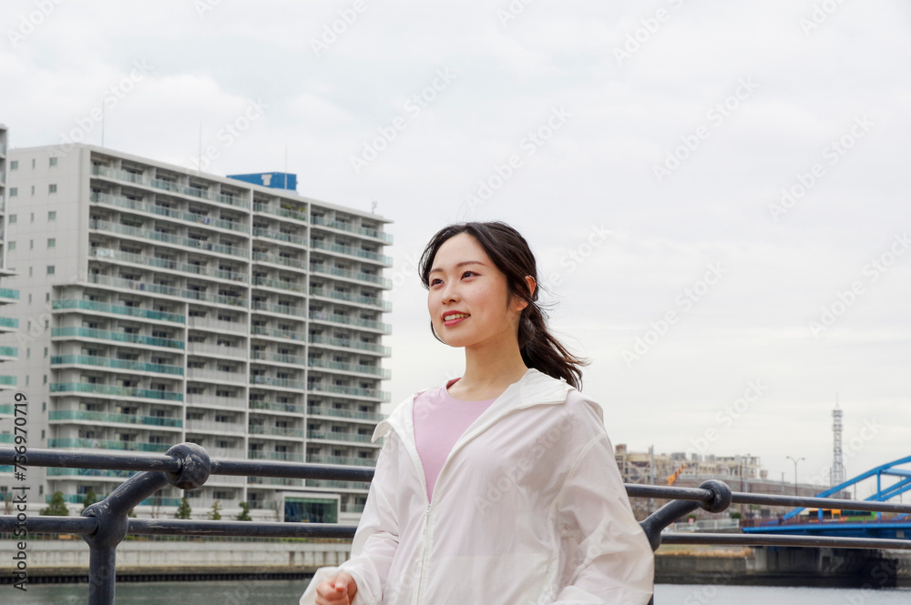 高層住宅が並ぶ遊歩道をウォーキングする女性 高層住宅が並ぶ遊歩道をウォーキングする女性