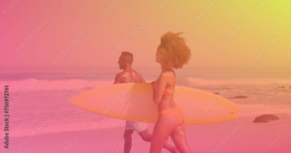 Obraz premium Image of happy couple at beach on sunny day carrying surfboards over colourful light