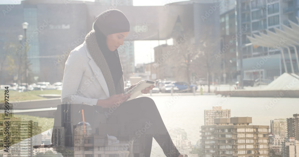 Image of asian woman in hijab using tablet over cityscape Image of asian woman in hijab using tablet over cityscape