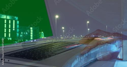Image of hands of woman using laptop with green screen over sped up traffic in city at night